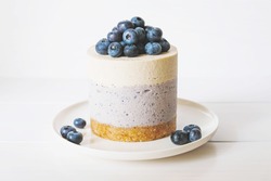 Raw gluten-free no-bake dessert. Vegan vanilla blueberry cheesecake against white background. Sweet healthy food.