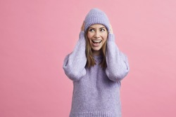 Young woman looking cute with sweater and matching hat on colorful background