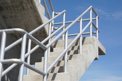 Selective focus steel handrail for accident prevention installed on concrete stairs to support engineering at water gate. Sky background. Steel handrail, accident prevention, concrete stairs concept.