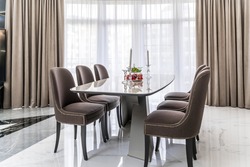 Oval light modern table and chairs with dark upholstery. A room in a minimalist style