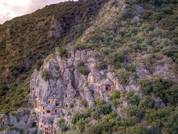 High angle drone aerial view of ancient greek rock cut tombs carved into cliffside in Myra (Demre, Turkey)