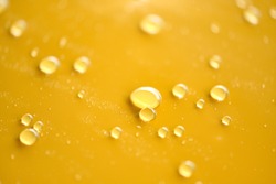 Water droplets on surface of yellow car paint. Car detailing concept. Natural patterns of droplets on paint panel. Rain drops wallpaper. Wet car shot during car wash. Selective focus. Shallow DOF