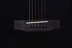 Closeup black acoustic guitar bridge studio shot on black background with copyspace, Guitar is favorite music instrument for hobby.