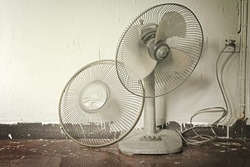 Dirty broken old electric fan in hot weather. Process in warm tone color.