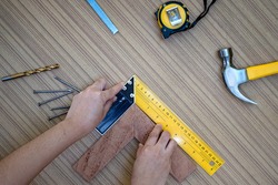 Female hands using a try square to check that the woodworking corners are square with a set collection of working hand tools for the wooden, Toolset with the do it yourself (DIY)