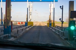 open barrier at a checkpoint on a toll road. green traffic light allowing traffic. View through a car windshield