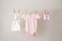 Baby clothes hanging on the rope on gray background.