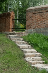 brick wall and stone steps leading to a metal gate