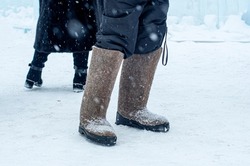 Winter footwear felt boots - close-up. A man stands in the winter on the street, in the snow in felt boots. Warm felt boots made of animal hair. Traditional shoes. Symbol of cold, frost.