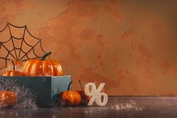 pile of orange halloween pumpkins with golden spider webs and branches. happy halloween party decoration on brown. Sale or discount with percentage sign. copy space