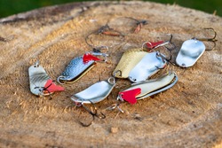 artificial metal baits on a wooden background. Homemade fishing gear. baits for catching large predatory fish. Items are made of different metal alloys of different colors and shapes