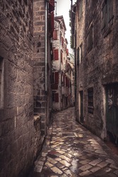 Medieval vintage narrow street with ancient stone pavers with medieval buildings in old european city Kotor in Montenegro 