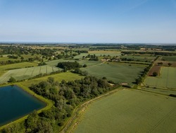 Aerial view of a patchwork of farm fields in the Suffolk countryside with a large reservoir in the foreground