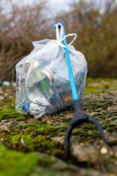 A litter picker and a full bag of rubbish that has been collected from a beach clean picking up discarded rubbish and litter. Litter pick, environmental, beach clean concept