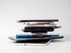 Old smartphones lie on top of each other. Stack of old mobile phones. Smartphones on a white background.