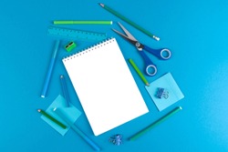 Flat lay of school office supplies on blue background with blank space for text