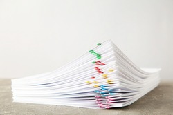 Stack of white paper with clips on grey background. Top view