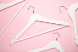 Many wooden white hangers on pink background. Store concept, empty hanger.