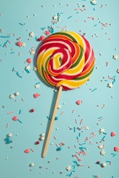 Colorful spiral lollipop with sprinkling on blue background. Top view