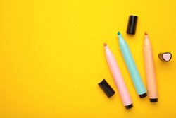 Open markers and space for text on yellow background. Pink, blue and orange highlighters