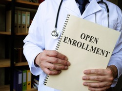 Doctor shows Annual open enrollment stack of papers.