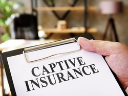 Hand holds documents Captive insurance about insurance.