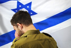 Israeli soldier crying in front of the flag of Israel