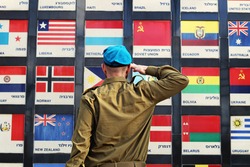 Israeli soldier salutes the flags of countries that voted the UN for the establishment of the State of Israel, country names on flags translated in Hebrew to English. Concept: Independence Day Israel