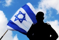Silhouette of an Israeli army soldier, IDF Soldier, on a blurred background with a waving Flag of Israel