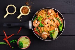 Fried Spaghetti or stir-fried noodles with vegetables and shrimp on a bowl on a dark black background, top view