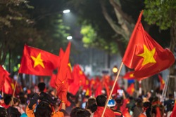 Blurred background of crowd of Vietnamese football fans down the street to celebrate the win after soccer, with a lot of Vietnamese flags raising high