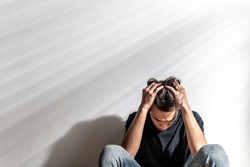 Male depression. Upset Asian young man having problems over white background, having heavy thoughts, break up with lover or financial difficulties Overthinking Unhappy unsatisfied and trouble concept.