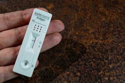 A hand holding a negative rapid antigen SARS-CoV-2 test.  It is a test for home use to check for antigens of a Covid-19 infection.