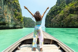Portrait of Young beautiful Asian woman standing on the boat passing beach lagoon in summer sunny day. Happy female relax and enjoy outdoor lifestyle on travel vacation at tropical island in Thailand