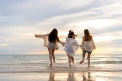  Group of Young Asian woman in walking and playing together on tropical beach at summer sunset. Happy female friends enjoy and fun outdoor activity lifestyle on holiday travel vacation at the sea