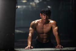 Portrait of Strong Asian sportsman athlete in sportswear do sport training workout bodybuilding exercise in abandoned building. Shirtless man bodybuilder practicing muscular build in dark place gym