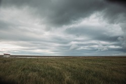 Beautiful icelandic landscape with dried grasses of fall and harsh stormy moody sky