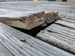 Wooden deck floor boards coming up that are old, warped and weathered, needing to be nailed and repaired