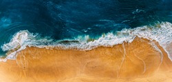 Beautiful sandy beach, top view. Panoramic view of the sandy beach. The sea wave rolls on the shore. Sea coast view from the air. Aerial photography of the sea wave. The ocean and beach. Copy space
