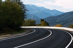 Asphalt road. Paved road on the background of mountains. Road on the background of beautiful mountains in the Caucasus. Landscapes of the country. Journey through beautiful places by car. Copy space