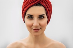 Portrait of a beautiful girl in a red turban on her head, close-up. Pretty close-up face of a fashionable woman. Portrait of a beautiful girl in oriental style. Portrait of a woman in a red turban