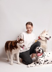 Dogs trainer, woman, among her three dogs, dalmatian and siberian husky isolated on white background. Trainer instructing dogs new teams. Dog training courses concept