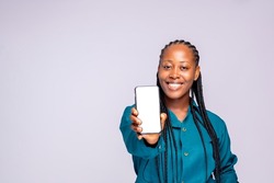 Portrait of a joyful African businesswoman showing blank screen mobile phone isolated over white background.