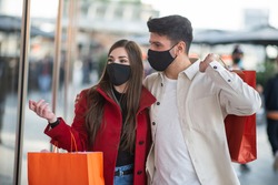 Covid and coronavirus shopping, young couple walking in a city while carrying shopping bags
