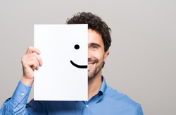Happy man covering half his face with a smiling emoticon