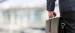Detail of a businessman holding a leather briefcase. Wide image with large copy-space