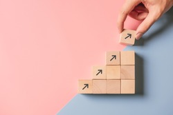 Business concept growth success process, Close up man hand arranging wood block stacking as step stair on paper blue and pink background, copy space.