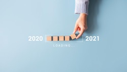 Loading new year 2020 to 2021 with hand putting wood cube in progress bar.