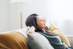 Closeup - Relaxed young asian woman enjoying rest on comfortable sofa at home, calm attractive girl relaxing and breathing fresh air in home, copy space.