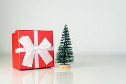 Little Christmas tree with Decorated X-mas Gift in Red box and White Ribbon. New year holidays concept with empty space for text